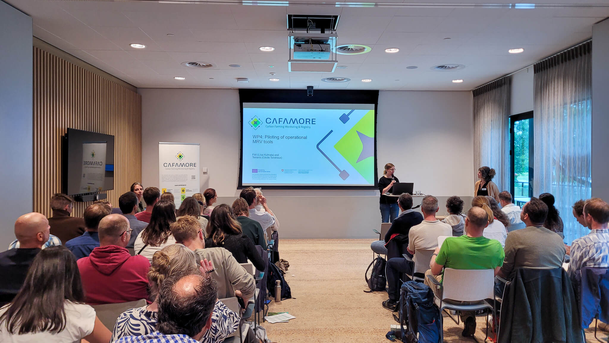 A group of people seated in chairs, attentively watching a presentation on a large screen in front of them.